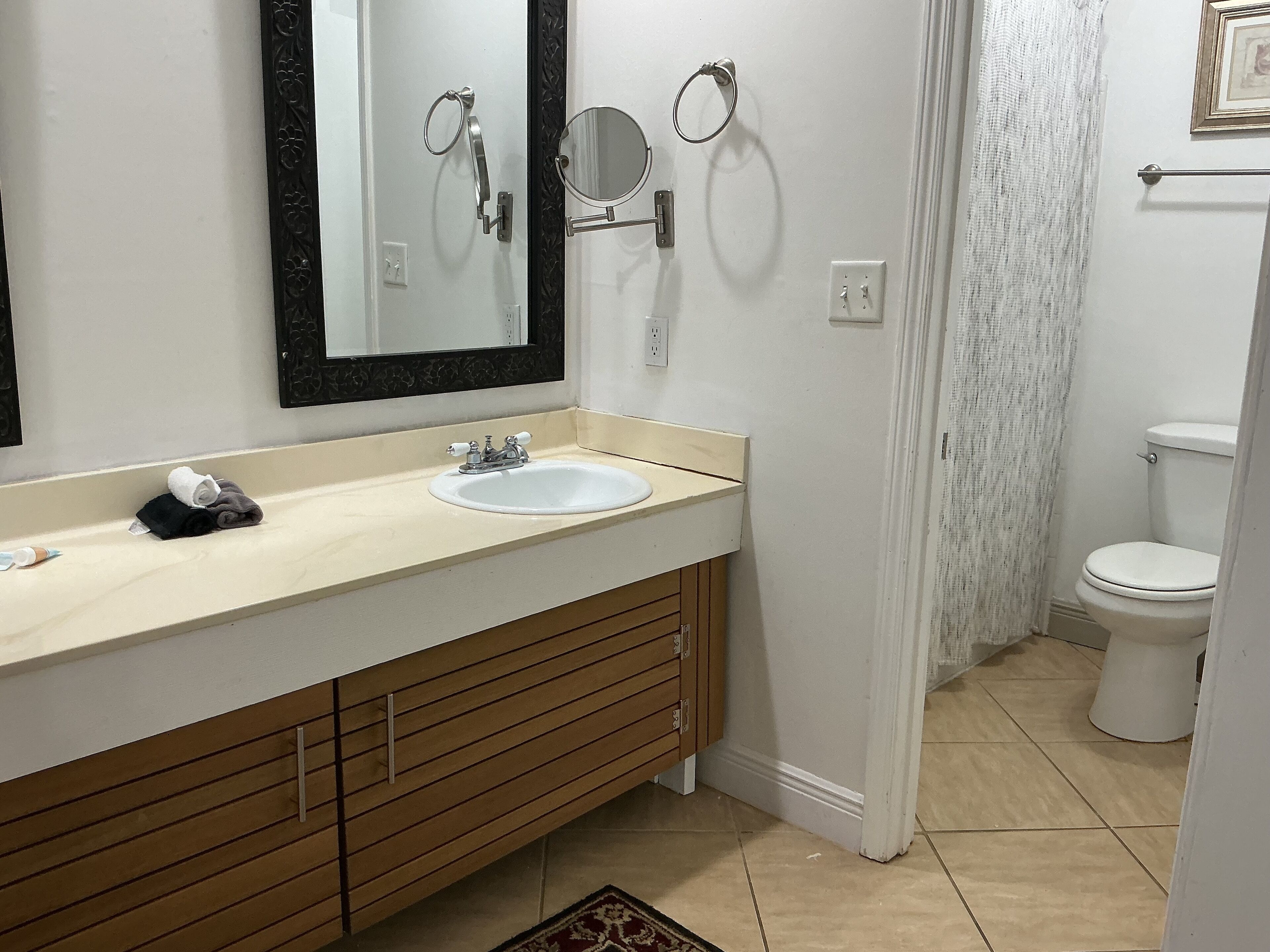 Une salle de bain avec un lavabo blanc, un meuble-lavabo en bois, deux miroirs et des toilettes.