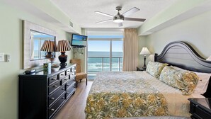 Ein Hotelzimmer mit Bett, Fernseher, Kommode und Meerblick.
