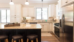 A modern kitchen with white cabinets, a stainless steel refrigerator, and a granite countertop.