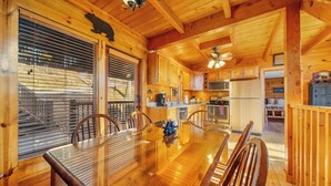 Interior de uma cabana de madeira com mesa de jantar, cadeiras e cozinha.