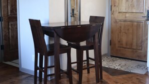 Un coin repas avec une table et des chaises en bois, un tableau encadré au mur et une porte en bois.