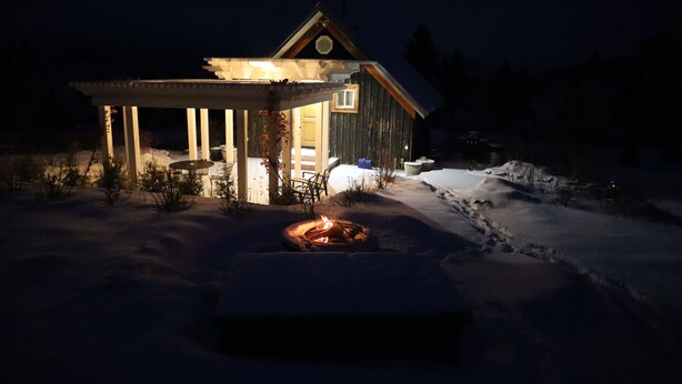 Une cabane en bois dotée d’un porche abrité, d’un foyer et d’un sentier enneigé menant à l’entrée.