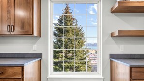 Eine Küche mit Holzschränken, einem Fenster mit Blick auf Bäume und Gebäude sowie einer Arbeitsplatte.