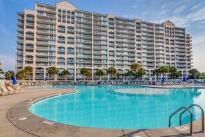 A large hotel with multiple balconies and a central swimming pool.