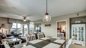 A dining area with a glass-top table, white chairs, and a ceiling fan. - 3rd Floor Marina View. Hot Tubs, Pool, Near Golf | Barefoot North Tower - 301 (North Myrtle Beach)
