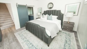 A bedroom with a large bed, a dresser, a nightstand, a mirror, and a door. - 💎 Blue Skies Ahead 💎- POOL IS OPEN!!! (Washington)