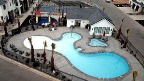 A swimming pool with a unique design, surrounded by a fence and palm trees. There are lounge chairs and a small building nearby. - 💎 Blue Skies Ahead 💎- POOL IS OPEN!!! (Washington)