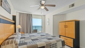 Une chambre d’hôtel avec un lit, un ventilateur de plafond, une armoire et une vue sur la mer.