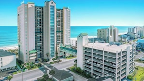 Hotel com vários andares, garagem, vista para a praia e uma passarela para pedestres.