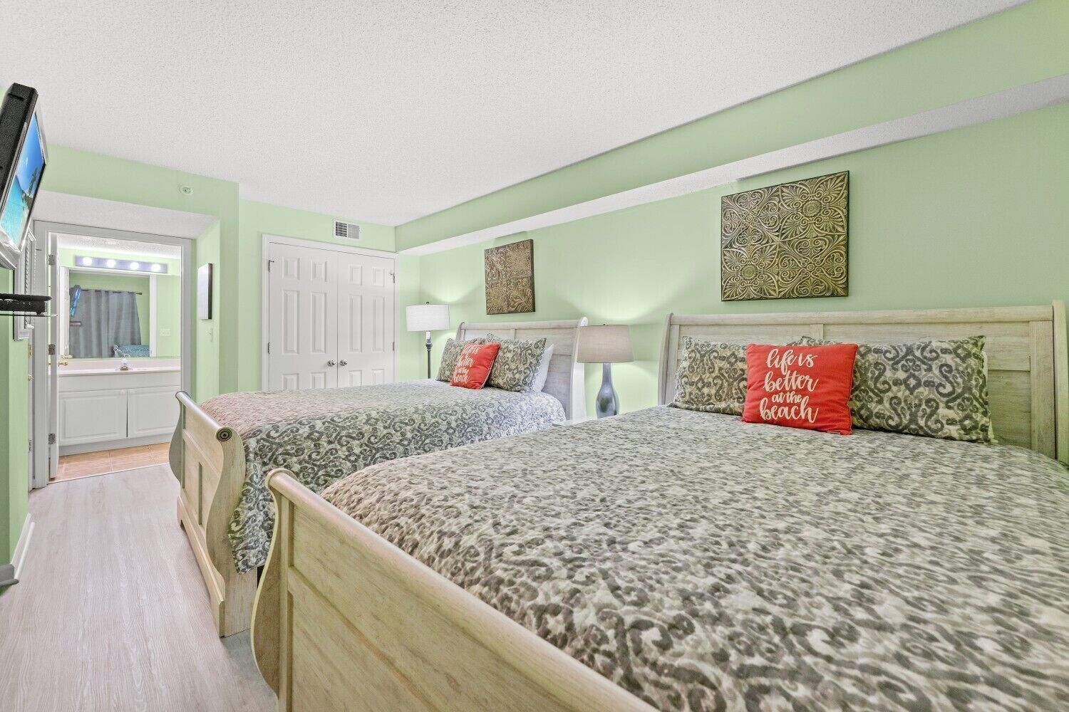 A hotel room with two beds, a bathroom, and a television.