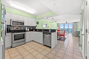 A kitchen with a central island, a dining area with a view, and a balcony with a view. - Spacious Updated Condo, Jacuzzi Tub, Lazy River | Windy Hill Dunes - 1203 (North Myrtle Beach)