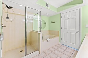A bathroom with a glass-enclosed shower, a bathtub, and a white door.