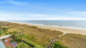 A beach view with a wooden boardwalk leading to a sandy beach. - Upscale Oceanfront Condo, Jacuzzi Tub, Lazy River | North Shore Villas - 405 (North Myrtle Beach)