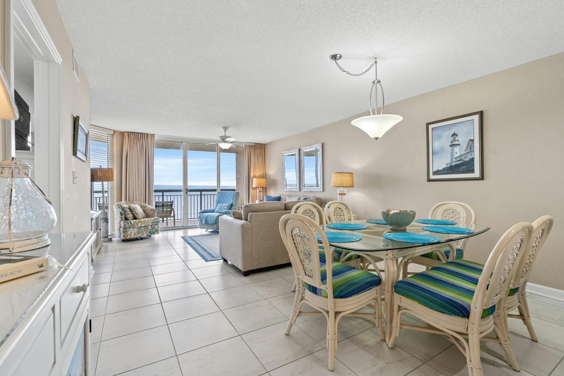 A spacious living area with a balcony, a dining table with chairs, and a view of the ocean.