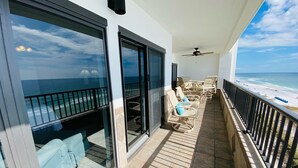Ein Balkon mit Meerblick, ausgestattet mit Stühlen und einem Tisch, sowie einem Deckenventilator.