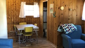 Un intérieur en bois comprenant une table à manger, des chaises, un canapé bleu et un tapis à motifs.