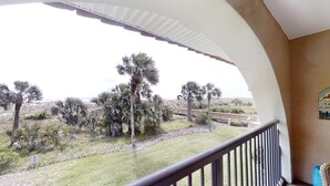 A balcony with a view of palm trees and a distant road. - Ponce Landing 5 - Ocean front 2 bedroom townhome with garage (St. Augustine)
