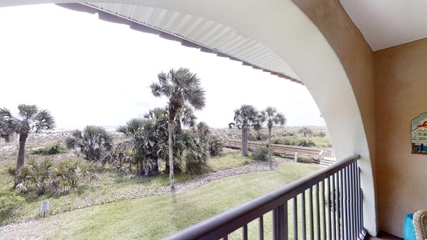 A balcony with a view of palm trees and a distant road. - Ponce Landing 5 - Ocean front 2 bedroom townhome with garage (St. Augustine)