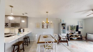 A modern kitchen with white cabinets, a central island, and pendant lighting. - Ponce Landing 5 - Ocean front 2 bedroom townhome with garage (St. Augustine)