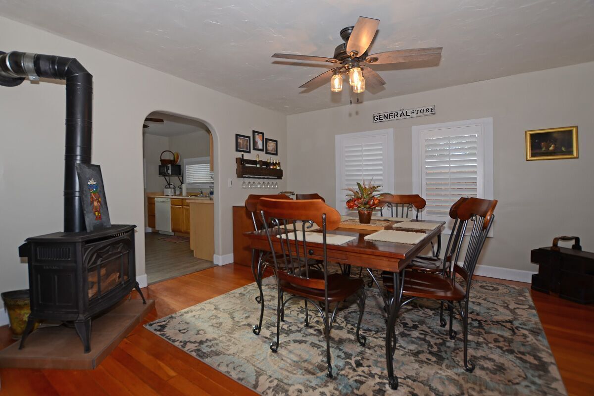 A dining area with a wooden table and chairs, a ceiling fan, and a black stove.