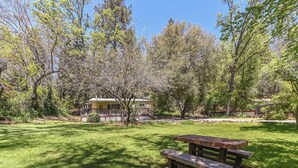 Un tavolo da picnic in una zona erbosa, con alberi e una casa sullo sfondo.
