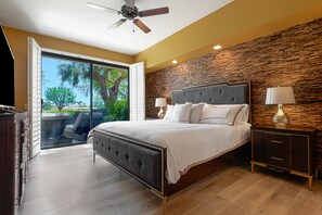 Une chambre avec un grand lit, une table de chevet, une lampe et une vue sur l’extérieur grâce à une porte-fenêtre coulissante.