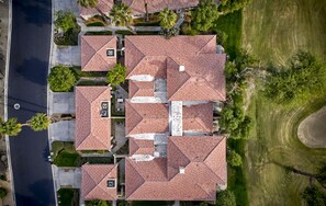 Een overzicht vanuit de lucht van een woonwijk met meerdere huizen, voorzien van rode dakpannen, omringd door groen en een weg.