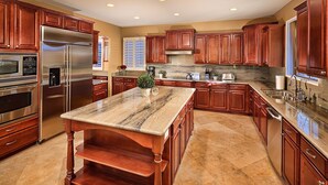 A spacious kitchen with wooden cabinets, stainless steel appliances, and a marble island. - Unbeatable Location, Heated Pool, 2 Primary Suites, Game Room, Hot Tub, More! (Phoenix)