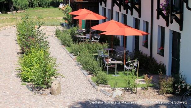 A traditional building with outdoor seating and red umbrellas. - Landhaus Masurische Schweiz (Kowale Oleckie)