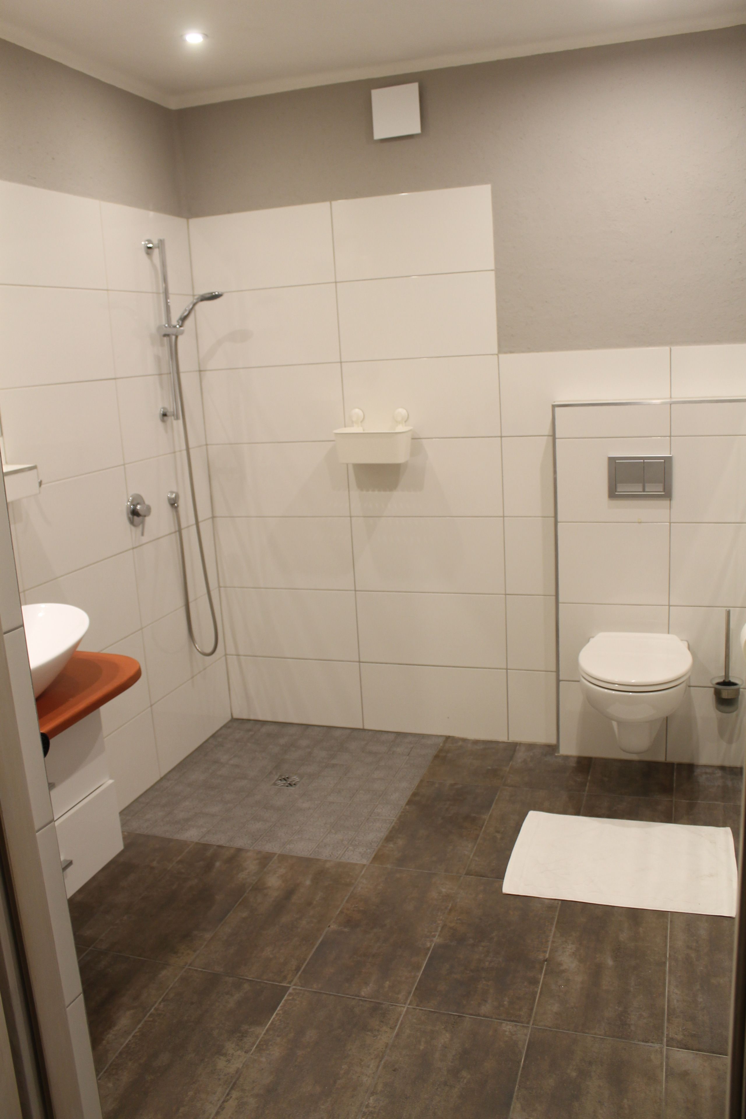 A modern bathroom with a shower, toilet, and sink.