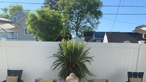A poolside seating area with two sofas, a small ottoman, and a Buddha statue centerpiece. - Walking Distance to Ocean/Beaches, Heated/Saltwater pool-pool open 4/1-11/1 (Rehoboth Beach)