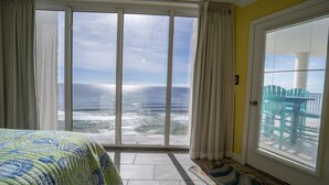 A room with a large sliding glass door leading to a balcony with a view of the ocean.
