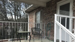 A covered patio with a table and chairs, a hose, and a white railing. - Road Dawg Condo  Welcome to God's country.  (Starkville)
