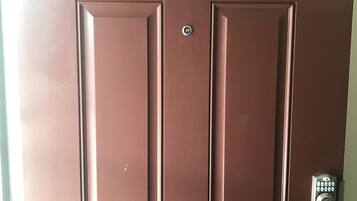 A brown door with the number 67, a keyhole, and a doorbell.