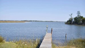 A wooden dock extending into calm water with a clear sky above. - 3BR Waterfront Home Fishing Boating Views (Stacy)