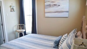 A bedroom with a bed, pillows, a chair, a wall art piece, and a window with curtains. - 3BR Waterfront Home Fishing Boating Views (Stacy)