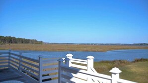 A wooden deck with white railings overlooking a body of water and a line of trees. - 3BR Waterfront Home Fishing Boating Views (Stacy)