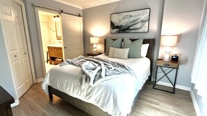 A bedroom with a bed, bedside lamps, a nightstand, a painting, and a door leading to another room. - Steps from the Mountain, in the iconic Old Town of Park City-2BR/2BTH Condo  (Park City)