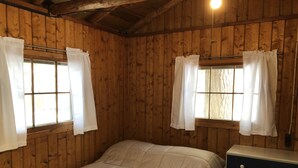 Ett rum med träpanel på väggarna, en säng och en byrå.