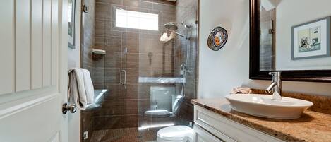 A modern bathroom with a glass-enclosed shower, a white sink, and a large mirror.