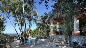 A pool area with lounge chairs, palm trees, and a view of the ocean. - Caracol Estates (Sayulita)
