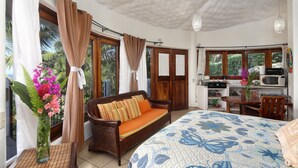 A bedroom with a bed, a sofa, a dining table, and a kitchenette. - Caracol Estates (Sayulita)