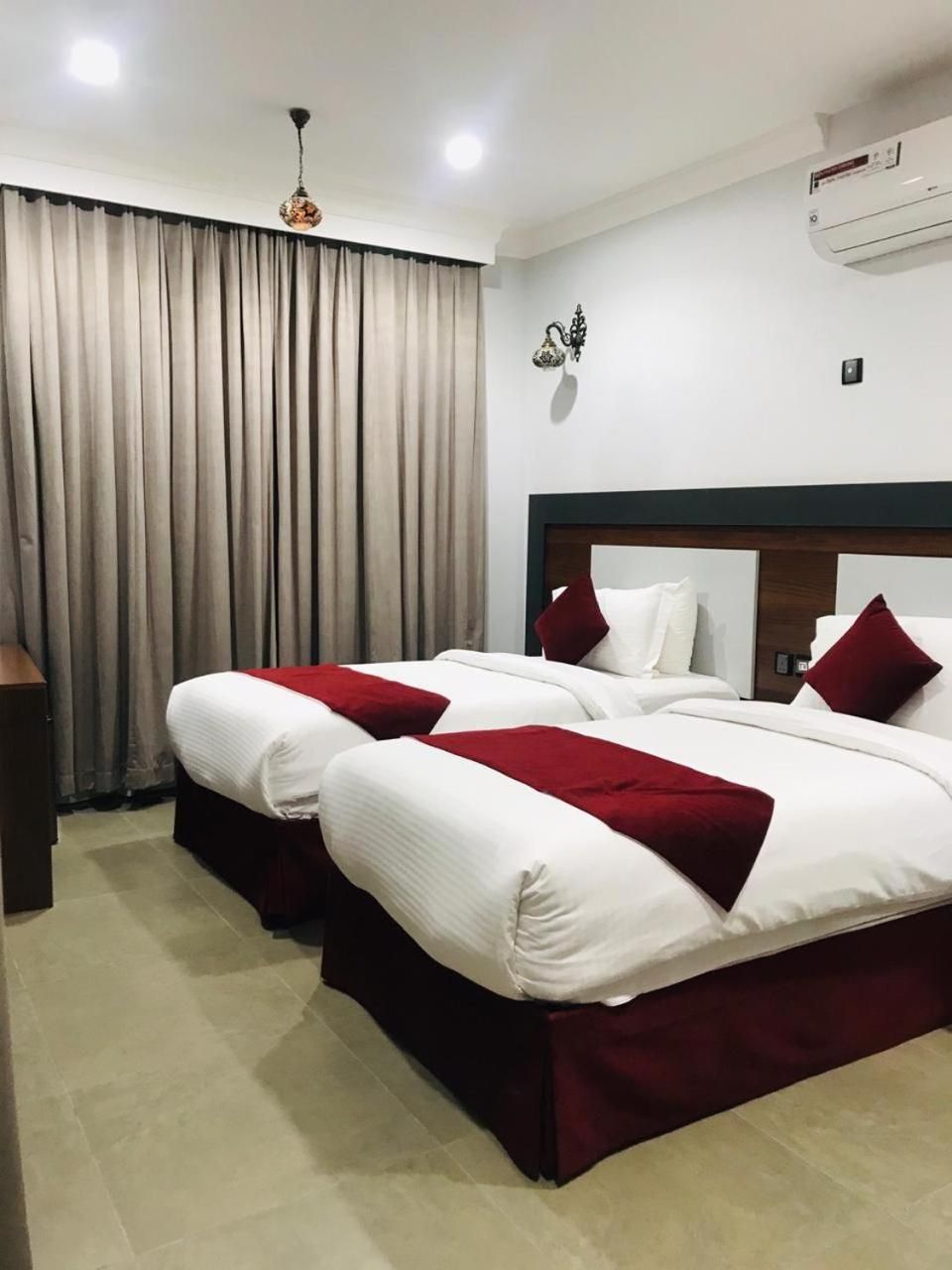 A hotel room with a double bed, a bedside table, a lamp, and a window with curtains.