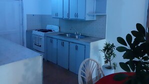 A compact kitchen with white cabinets, a stove, and a sink.