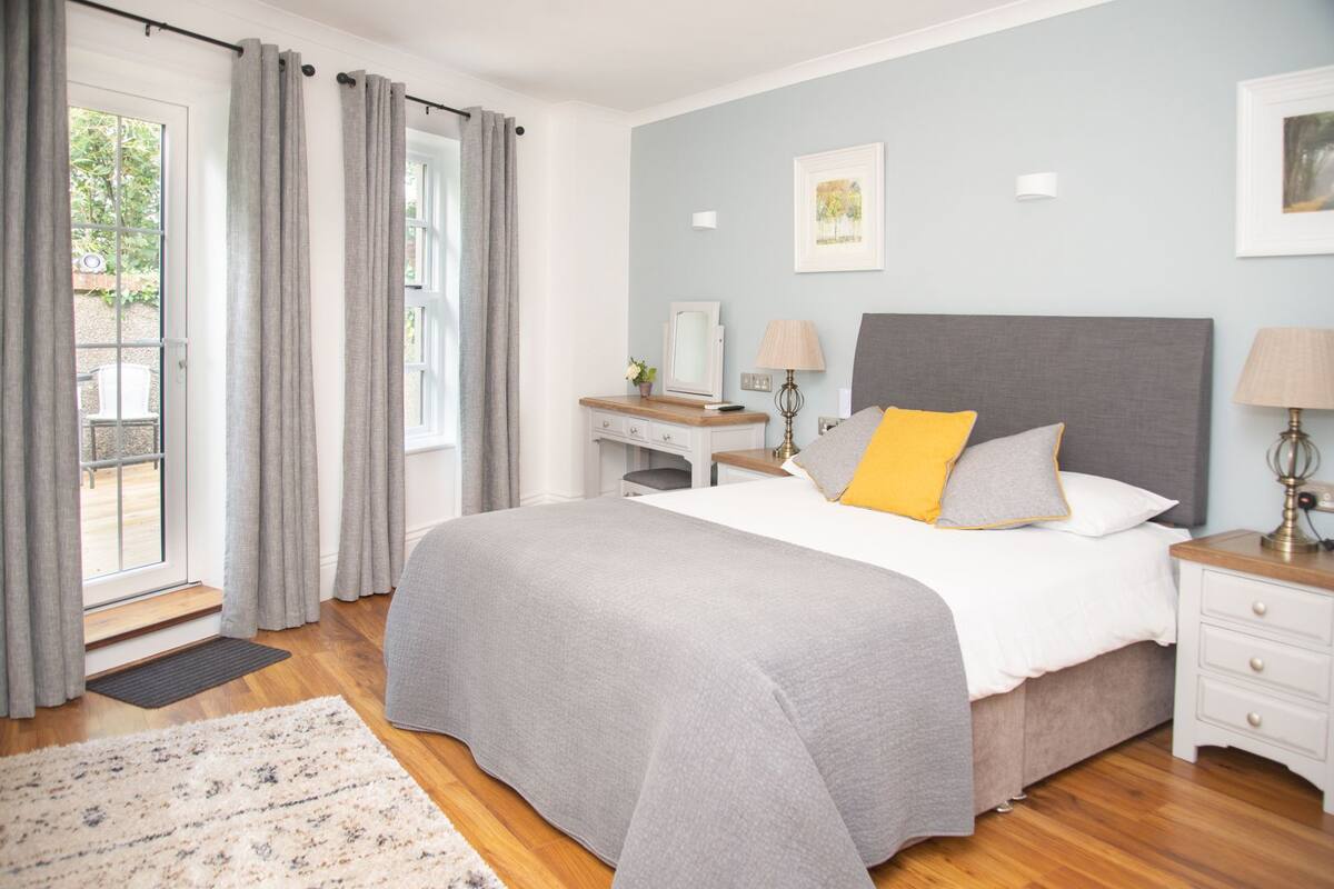 A bedroom with a bed, bedside tables, a desk, and a window with curtains.