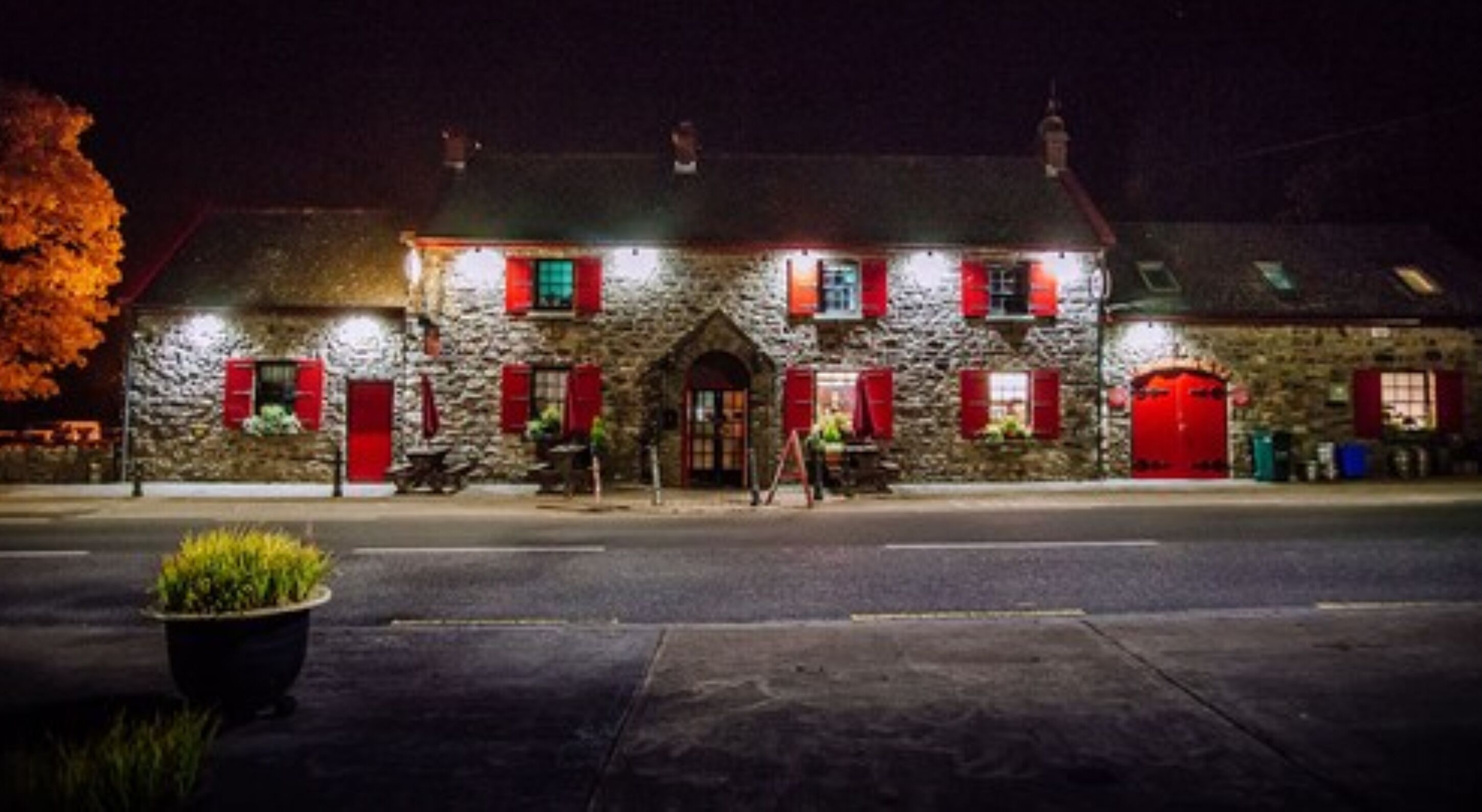 A stone building with red shutters and a central entrance.