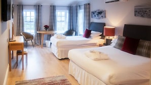 Una habitación de hotel con dos camas, un escritorio, una silla y una mesita.