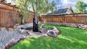 A backyard with a wooden fence, a stone retaining wall, a tree, and a rock garden. - Great location in Old Mill District ! ♥ Fenced Backyard,  ♥ Pet Friendly! (Bend)