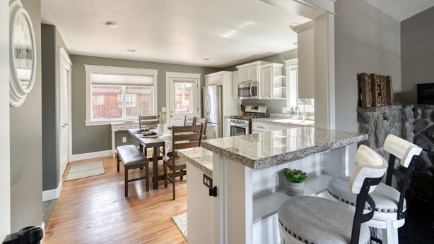 A modern kitchen with white cabinetry, a granite countertop island, and a stone fireplace. - Great location in Old Mill District ! ♥ Fenced Backyard,  ♥ Pet Friendly! (Bend)
