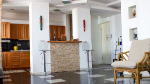 A modern living room with a stone fireplace, wooden cabinets, and a wicker chair. - Tbilisi Center Private 4-room Apartment (Dzveli Tbilisi)
